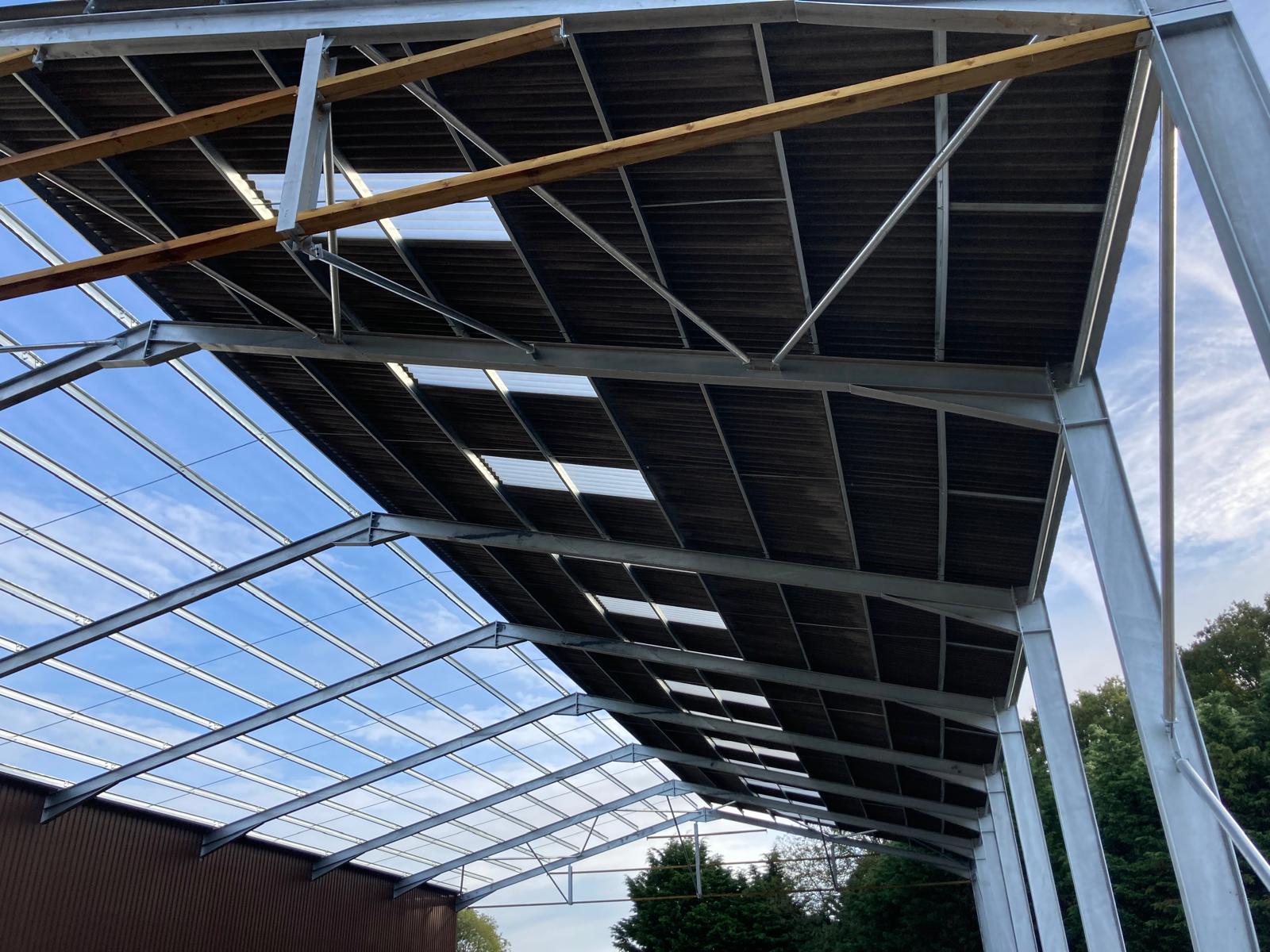 Agricultural steel-frame building with new roof structure being installed