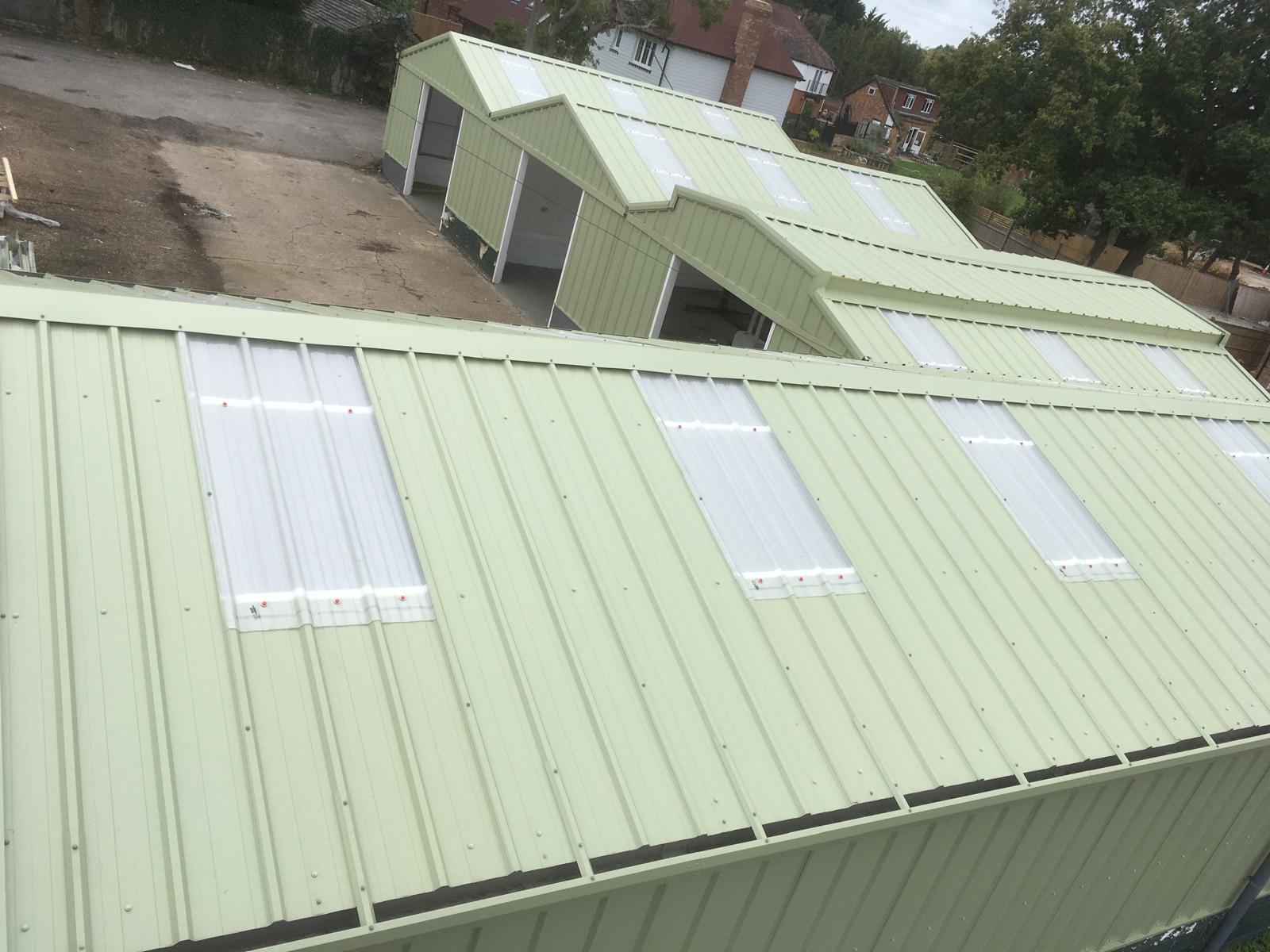 Sage-green over-clad commercial roof with translucent rooflights