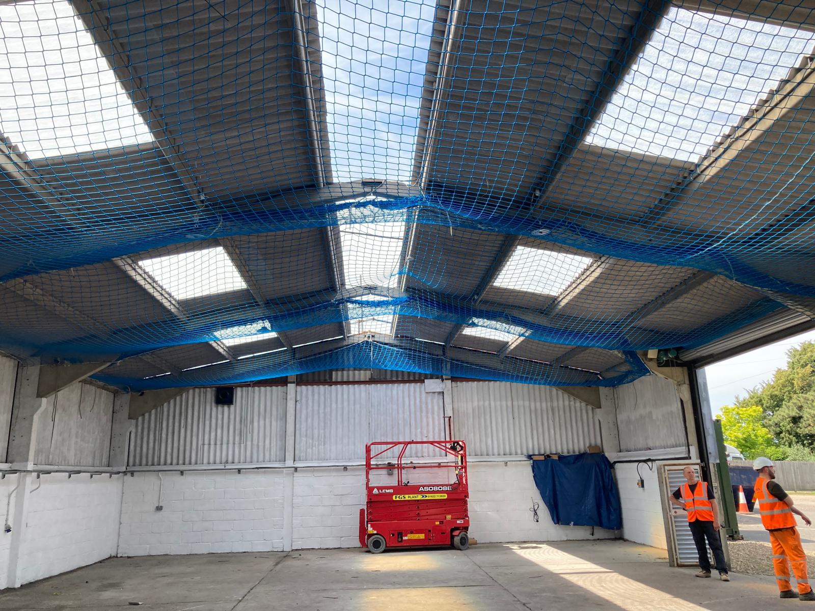 Interior of agricultural building showing safety netting installed beneath fragile roof