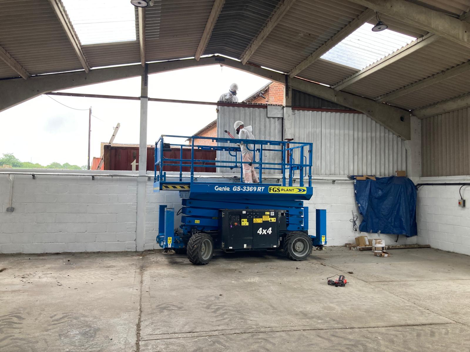 Asbestos removal operatives in PPE on a scissor lift